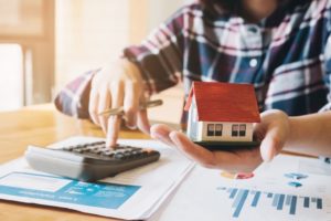 A man using a calculator to calculate budget for his dream house